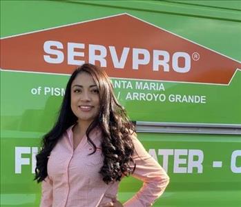 Female smiling with light orange shirt, green SERVPRO van in background 